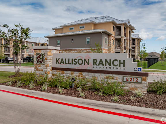 A sign for Kallison Ranch Apartments is in front of a building.