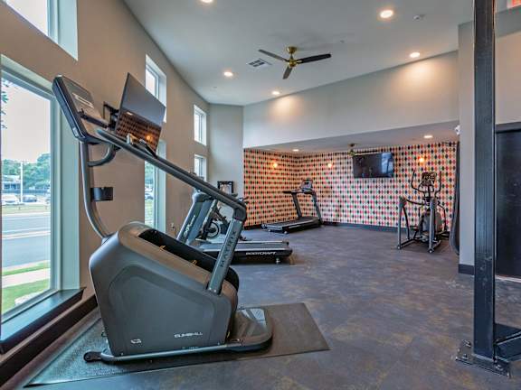 A treadmill is in a room with a ceiling fan and a window.
