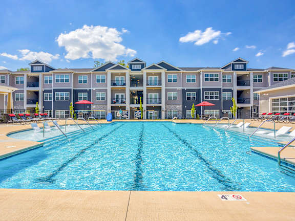 A large swimming pool in front of a multi-story apartment building.