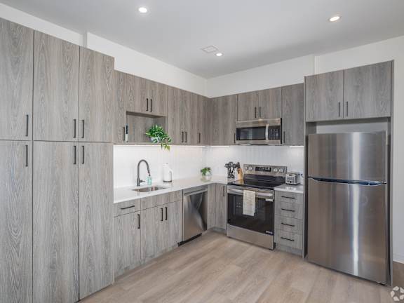 A kitchen with stainless steel appliances and wooden cabinets.at The Jones Tower at the Collective, Pittsburgh, PA