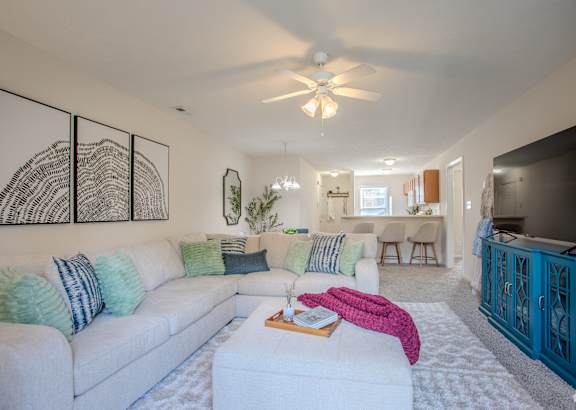 A living room with a white couch and a ceiling fan.