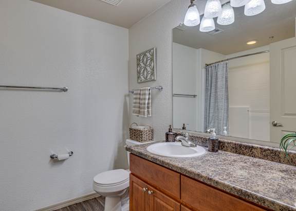 A bathroom with a toilet, sink, and mirror.