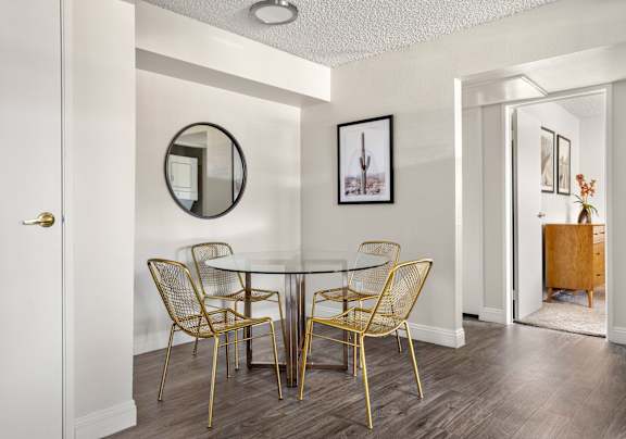 A dining room with a white table and gold chairs.
