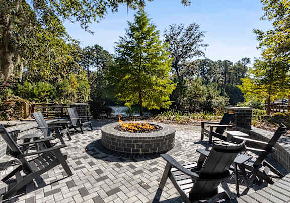 A fire pit in the middle of a patio surrounded by chairs.