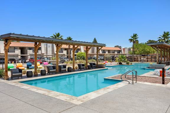 a swimming pool with lounge chairs and umbrellas at the retreat at thousand oaks apartments