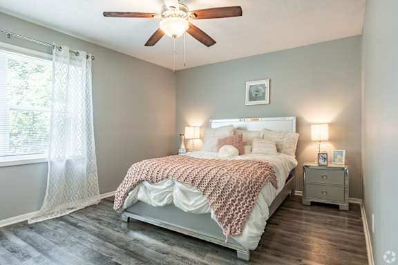 A bedroom with a bed, nightstands, and a ceiling fan.
