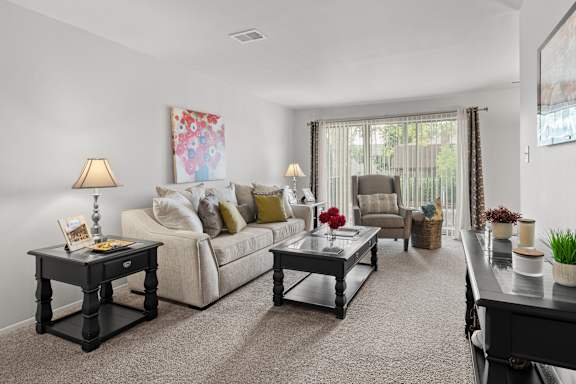 A living room with a white couch, a coffee table, and a painting on the wall.