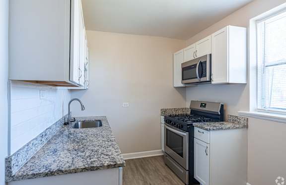 A kitchen with granite countertops and white cabinets.