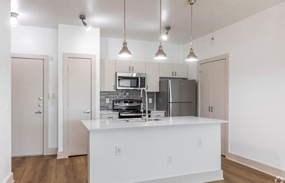 A kitchen with white cabinets and a white island with a microwave and oven built into it.