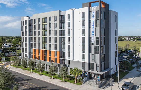 A modern multi-story building with a sign that reads "NOW LOW PRICES".