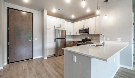 A modern kitchen with a wooden door and stainless steel appliances.