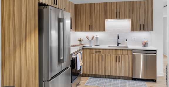 A modern kitchen with wooden cabinets and a stainless steel refrigerator.