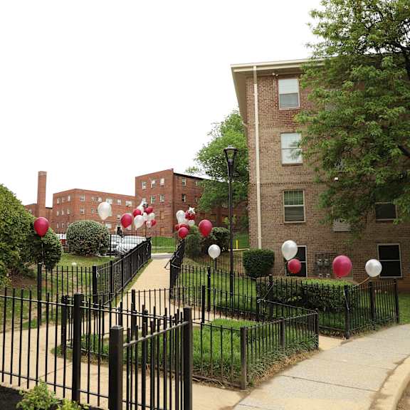 a black wrought iron fence with red and white balloons in front of a brick building