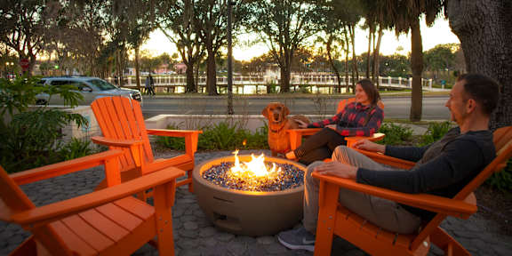 A man and woman sitting by a fire pit in a park.