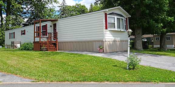 A mobile home with a red door and a deck.