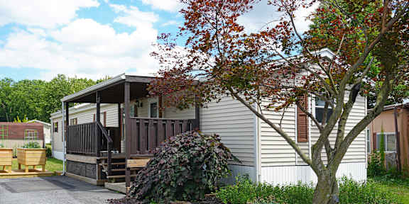 A house with a porch and a tree in front.