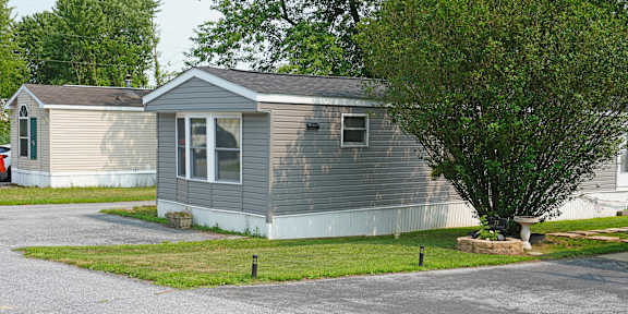 A grey house with a tree in front.