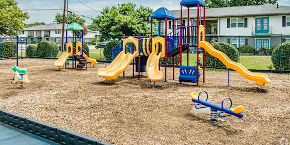 A playground with a blue and yellow slide and a green toy horse.