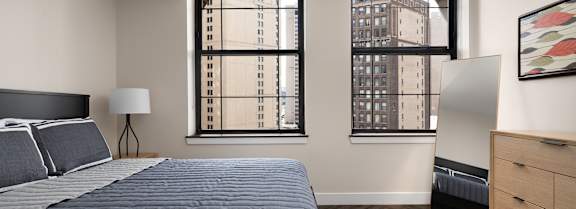 A bedroom with a large bed and a window overlooking a cityscape.