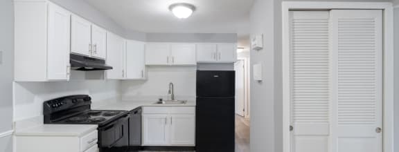 an empty kitchen with white cabinets and black appliances