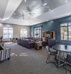 A spacious living room with a ceiling fan and a variety of seating options.