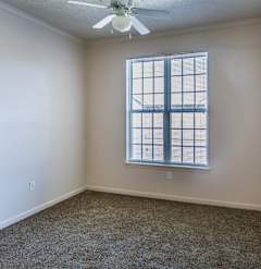 A room with a ceiling fan and a window with blinds.