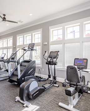 a gym with cardio equipment and windows