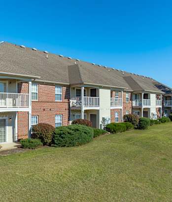 A row of apartment buildings with green lawns in front.