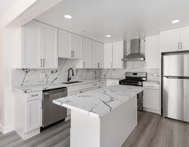 a kitchen with white cabinets and white marble countertops at Seaview Terrace Apartment Homes, California, 92672