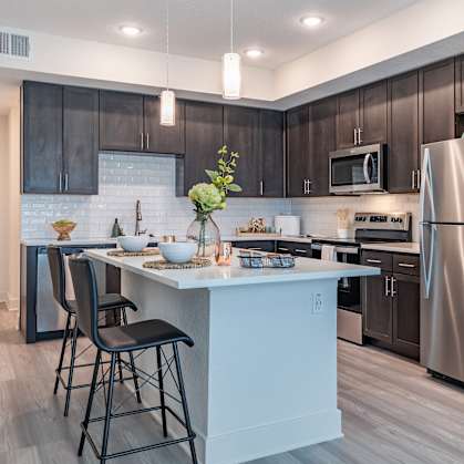 A kitchen with a white island and a stainless steel refrigerator.