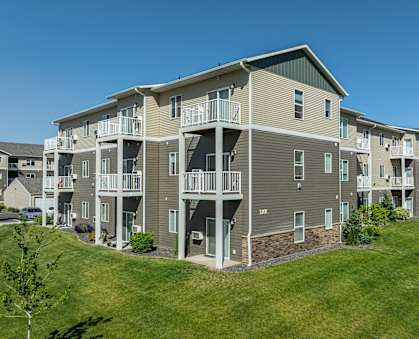 an exterior view of an apartment building with a green lawn