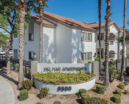 A white building with a red roof and a sign that says Del Mar Apartments.