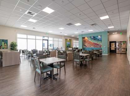 A large clubhouse with tables and chairs and a plant.