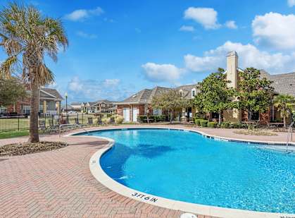 A swimming pool surrounded by a brick patio and palm trees.