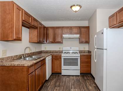 A kitchen with brown cabinets and white appliances.