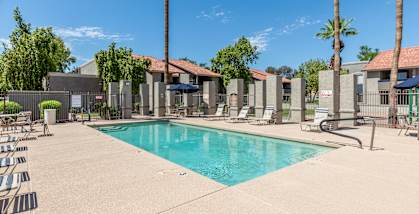 A swimming pool surrounded by palm trees and lounge chairs.