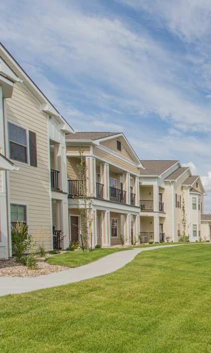 A row of houses with a grassy area in the foreground at The Retreat Apartment Homes in Williston, North Dakota