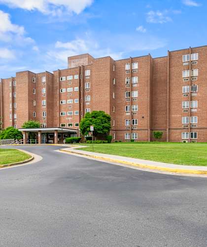 A large brick building with a curved driveway in front.