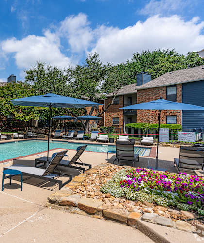 A pool surrounded by chairs and umbrellas with a building in the background.