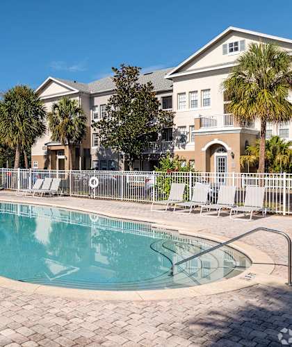A large swimming pool surrounded by a brick patio and lounge chairs.