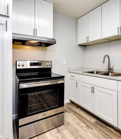 an empty kitchen with white cabinets and stainless steel appliances