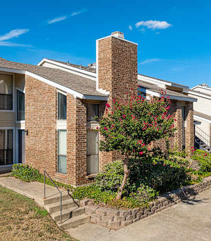 A row of brick apartment buildings with a tree in front.