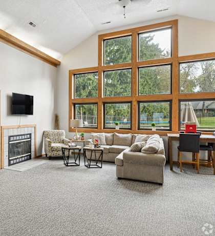 A living room with a grey carpet and a fireplace.