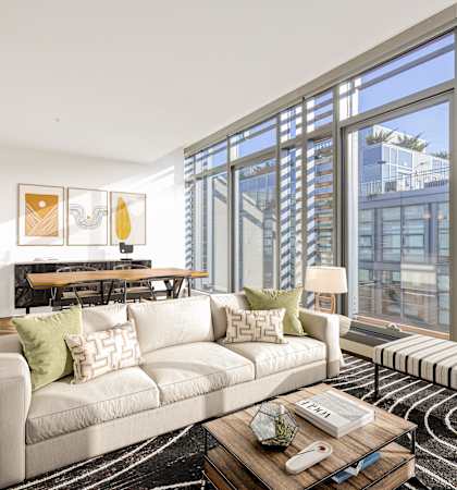 a living room with a couch and a table and large windows