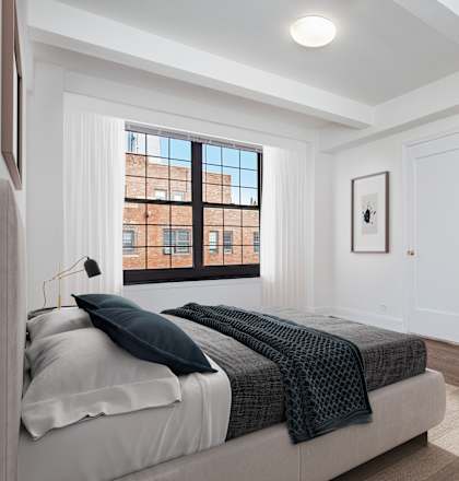 A bedroom with a large bed and a window overlooking a cityscape.