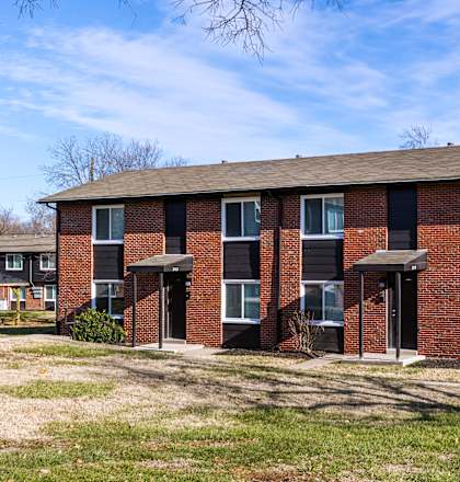 A red brick building with a brown roof and a white door. at Blacklark Apartments, Apartments, Kansas City, KS