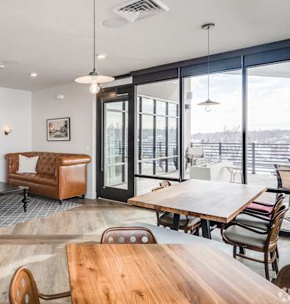 A modern living room with a flat screen TV, a coffee table, and a view of the outdoors.