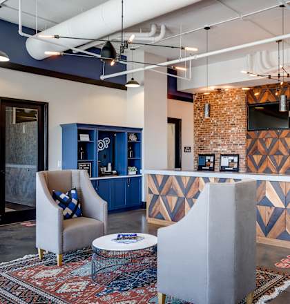 A modern office lobby with a brick wall and a reception desk.