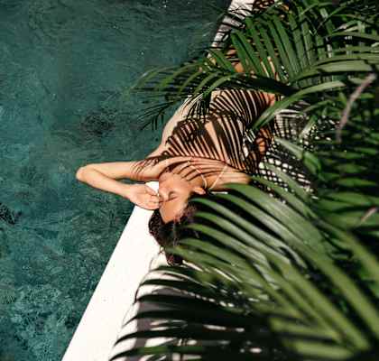 a woman laying in a pool next to a palm tree