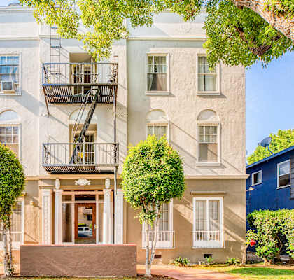 the front of a white house with two balconies and a lawn